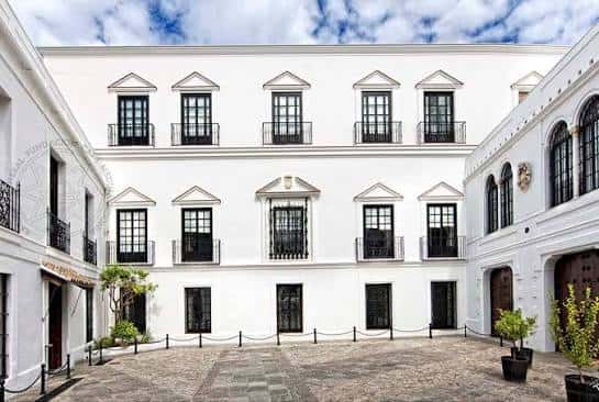 Patio principal de la Fundación Casa Medina Sidonia con fachada blanca y ventanas ornamentadas