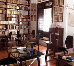Interior de la biblioteca histórica con estanterías llenas de libros y mobiliario clásico