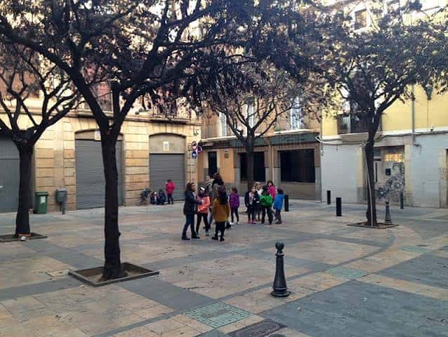 Grupo de personas reunidas en la plaza bajo los árboles
