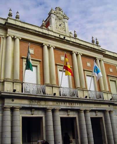 Detalle superior de la fachada con banderas y reloj del ayuntamiento