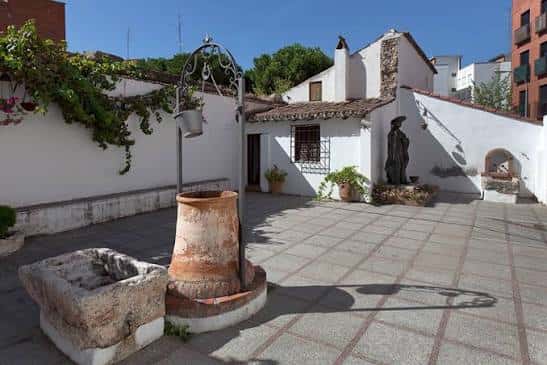 Patio interior con pozo y estatua del poeta