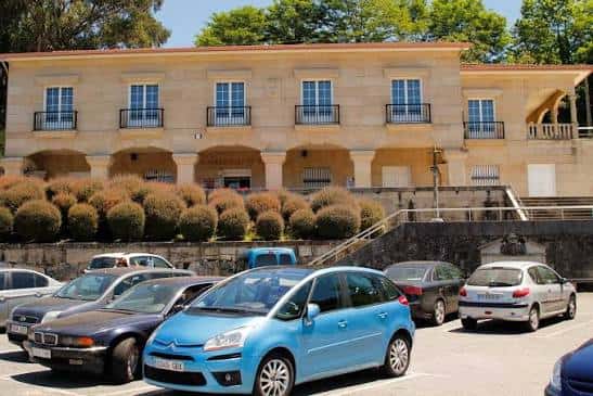 Edificio rodeado de aparcamiento y jardines bien cuidados