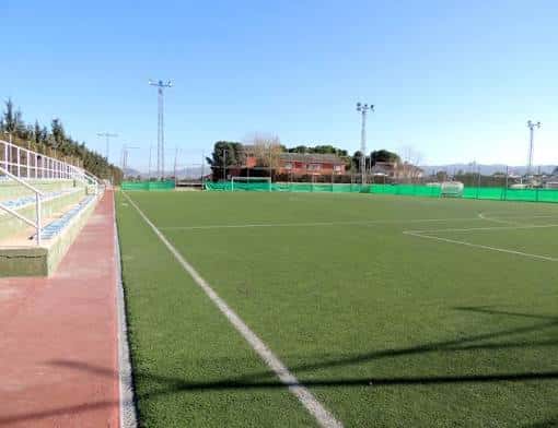 Campo de fútbol con césped artificial y gradas al aire libre
