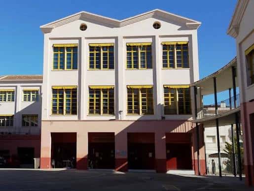 Fachada principal del Institut Municipal d'Educació i Treball (IMET) con ventanas amarillas y cielo azul