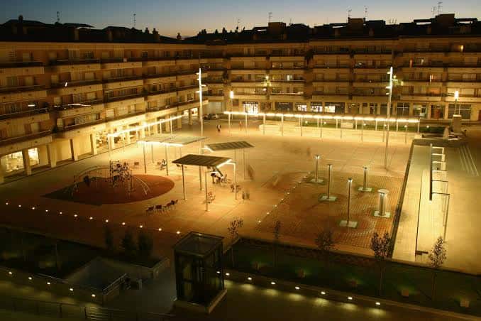 Vista nocturna de la Plaza Charlie Rivel con iluminación y zona de juegos