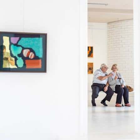 Interior de la galería con visitantes contemplando obras de arte