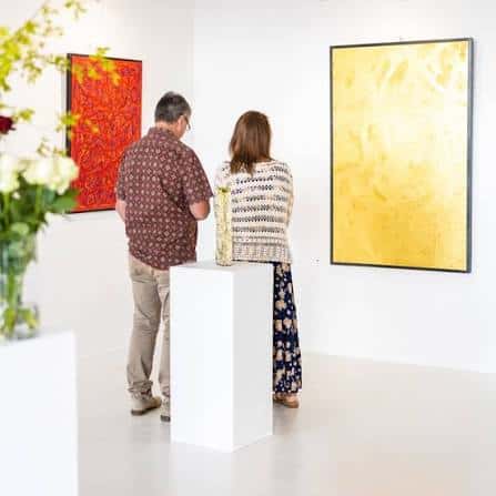 Pareja observando pinturas abstractas en una sala blanca