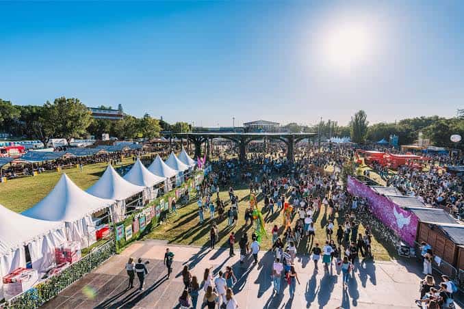 Vista aérea del recinto del festival con carpas blancas, zonas de comida y multitud caminando