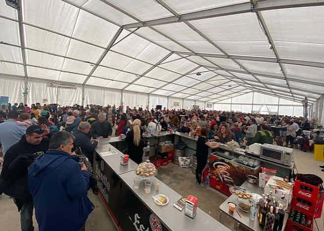 Vista interior de la Carpa Malvaloca con barra de comida y gente congregada en feria gastronómica