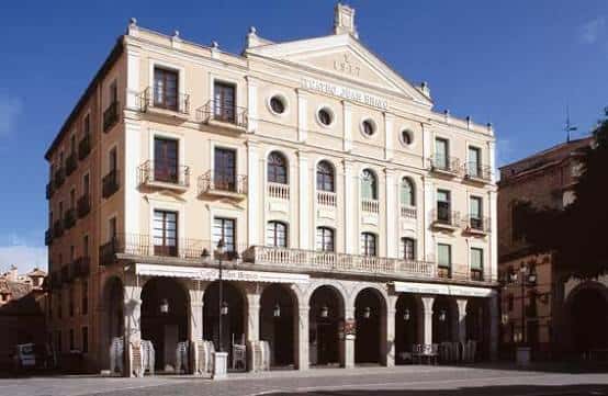 Fachada completa del Teatro Juan Bravo bajo cielo azul, mostrando su arquitectura clásica y balcones