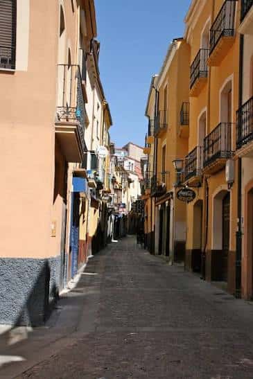 Calle empedrada de Los Herreros con edificios coloridos y balcones tradicionales bajo cielo despejado