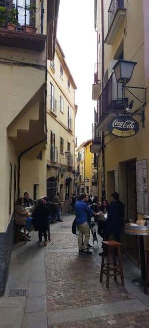 Vida cotidiana en la calle: personas sentadas en terrazas al aire libre entre arquitectura histórica