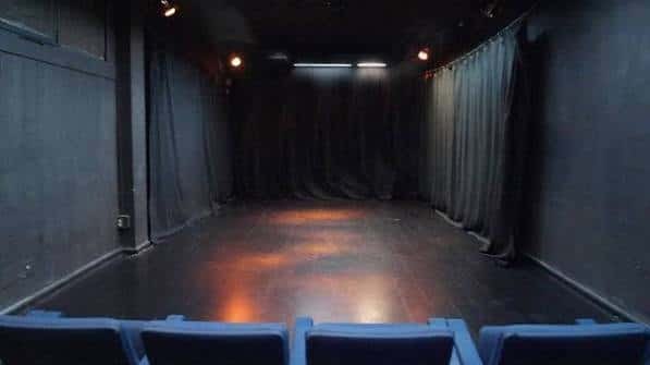 Escenario vacío con cortinas laterales y suelo de madera pulida