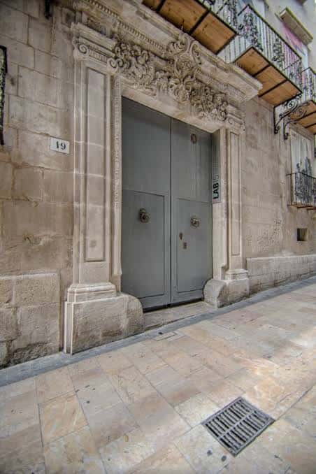 Vista exterior de la entrada principal del Palacio El Portalet con su imponente fachada de piedra y puerta gris