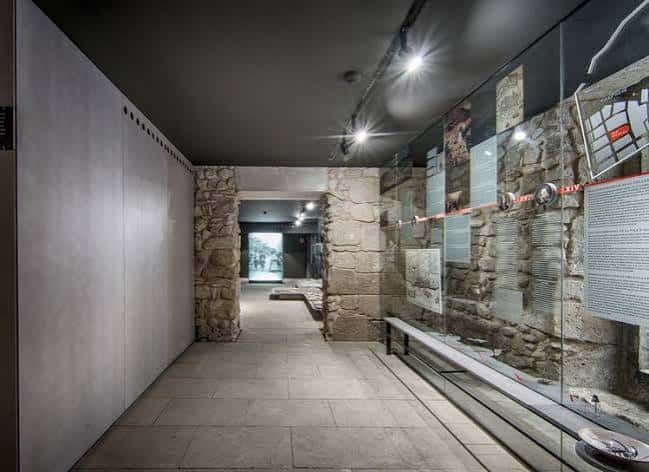Interior del palacio mostrando un pasillo con muros de piedra original y vitrinas expositivas modernas