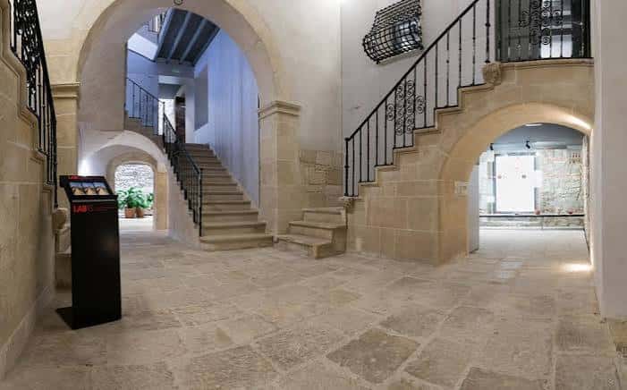Atrio interior del Palacio El Portalet con escaleras de piedra, arcos y barandillas de hierro forjado