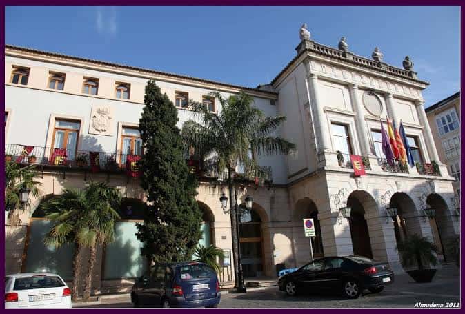 Vista diurna de la Plaza del Ayuntamiento con banderas y arquitectura clásica