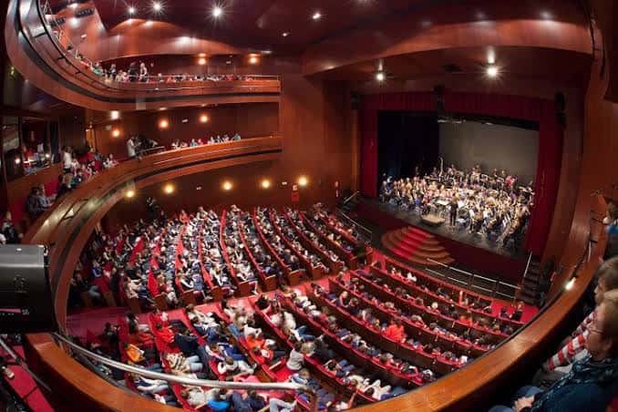 Interior del auditorio durante un concierto con público y orquesta en escena