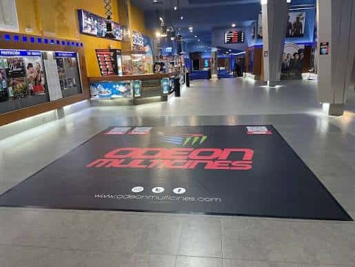 Interior del vestíbulo de Odeón Multicines con mostrador de taquilla y branding