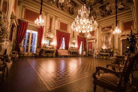 Gran salón de baile con candelabros y cortinas rojas