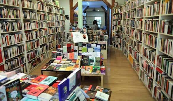 Interior acogedor de la librería Enclave con estanterías llenas de libros y mesas de exhibición