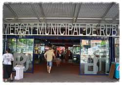 Entrada principal del Mercado Municipal de Rubí con letrero visible y personas accediendo