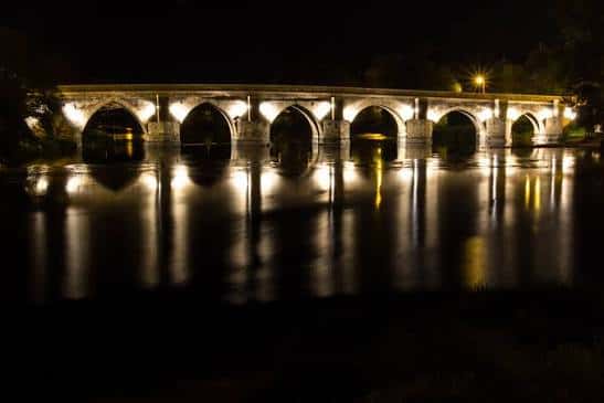 Puente Romano de Lugo iluminado por la noche reflejándose en el agua