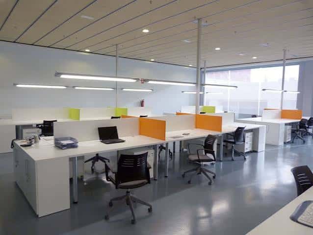 Vista general del espacio de coworking con escritorios modernos y separadores de colores