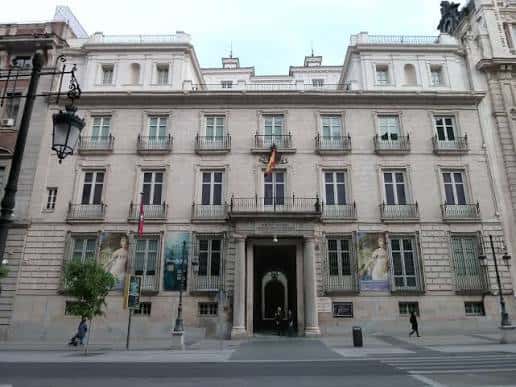 Vista frontal del palacio desde la calle Alcalá con farolas y peatones