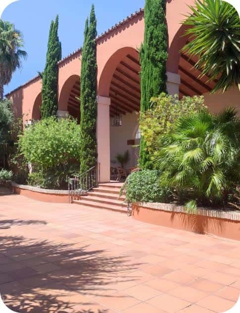 Exterior del edificio con arcos y jardines tropicales