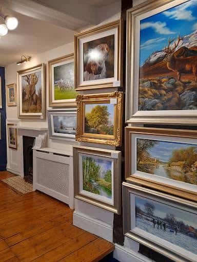 Vista del interior de la galería mostrando pinturas paisajísticas y decoraciones