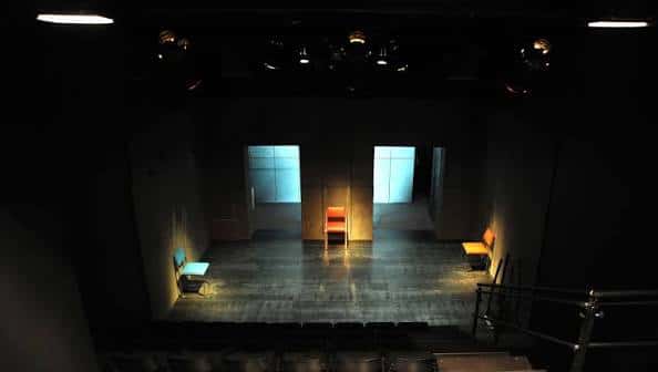 Vista del escenario principal con iluminación dramática y mobiliario minimalista