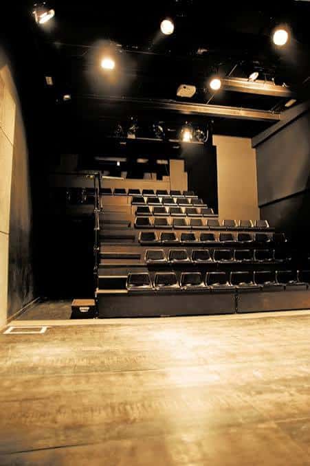 Escenario desde la perspectiva del público con asientos negros y sistema de luces superior