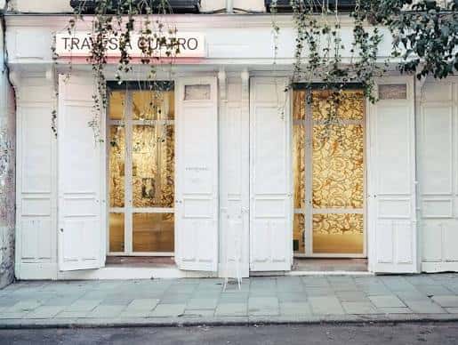 Fachada exterior de Travesía Cuatro con puertas blancas y decoración de enredaderas