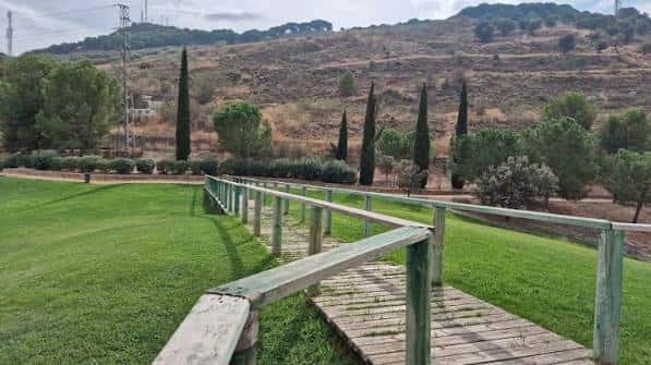 Sendero de madera y barandilla verde en el parque con vistas a las colinas