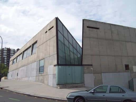 Ángulo lateral del edificio mostrando su arquitectura moderna en hormigón y grandes ventanales