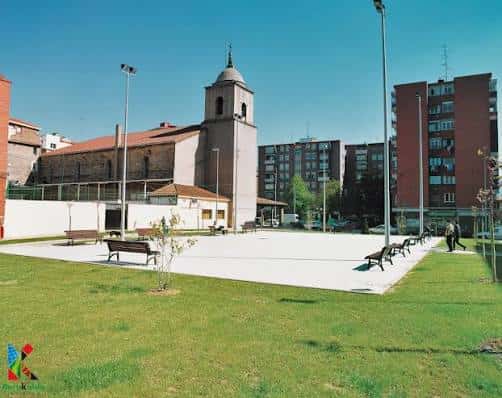 Plaza frente a la iglesia de San Vicente en Baracaldo con césped y bancos