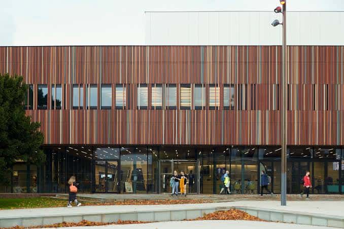 Vista exterior del Ravelin Sports Centre con fachada de listones de madera y cristal