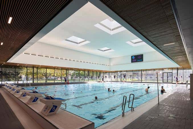 Piscina interior moderna con piscinas olímpicas y techos de claraboyas