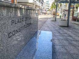Vista de la Plaza de la Constitución con su distintivo muro de granito y fuente