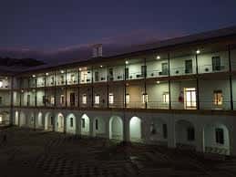 Vista nocturna del patio central del campus universitario con arcos iluminados