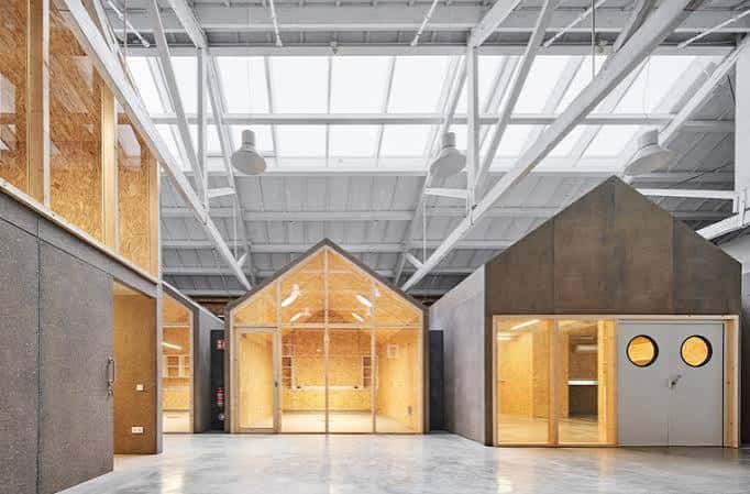 Vista interior del Ateneu de Fabricació de Gràcia mostrando las estructuras modulares de madera bajo la techumbre industrial