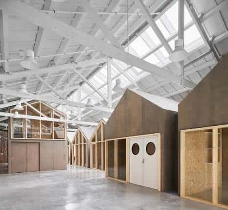 Espacio amplio y luminoso con vigas blancas y módulos de construcción prefabricada en el interior