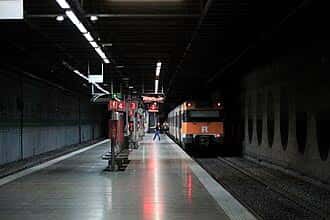 Andén de la estación con tren en servicio y señalización