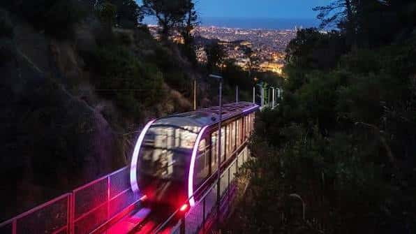 Funicular iluminado de noche con fondo urbano de Barcelona
