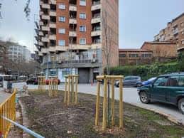 Vista de la zona enjardinada renovada en la Plaça Onze de Setembre con mobiliario urbano y edificios residenciales al fondo