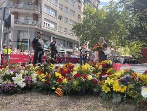 Ceremonia institucional en la plaza con flores conmemorativas, autoridades y público durante la Diada Nacional