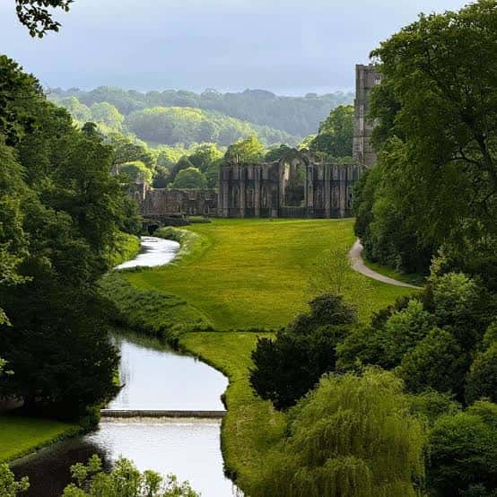 Vista panorámica de las ruinas de Fountains Abbey rodeadas de jardines y el río con reflejos