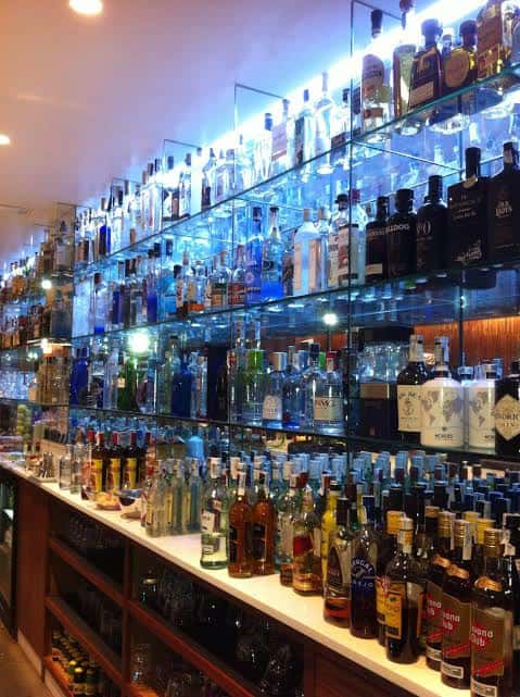 Estantería iluminada con amplia selección de bebidas en el bar
