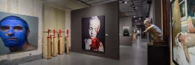 Exposición contemporánea con retratos grandes y esculturas en el museo
